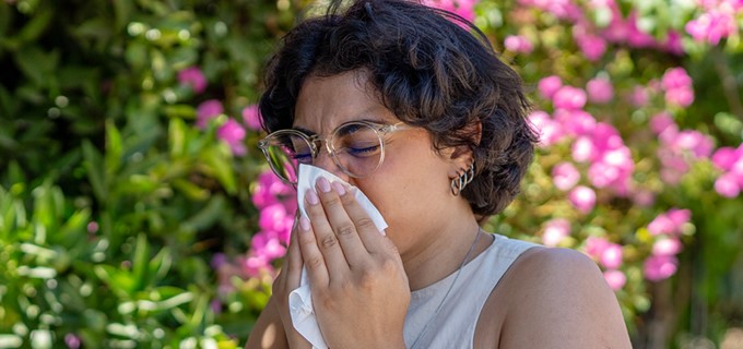 Women sneezing into tissue.